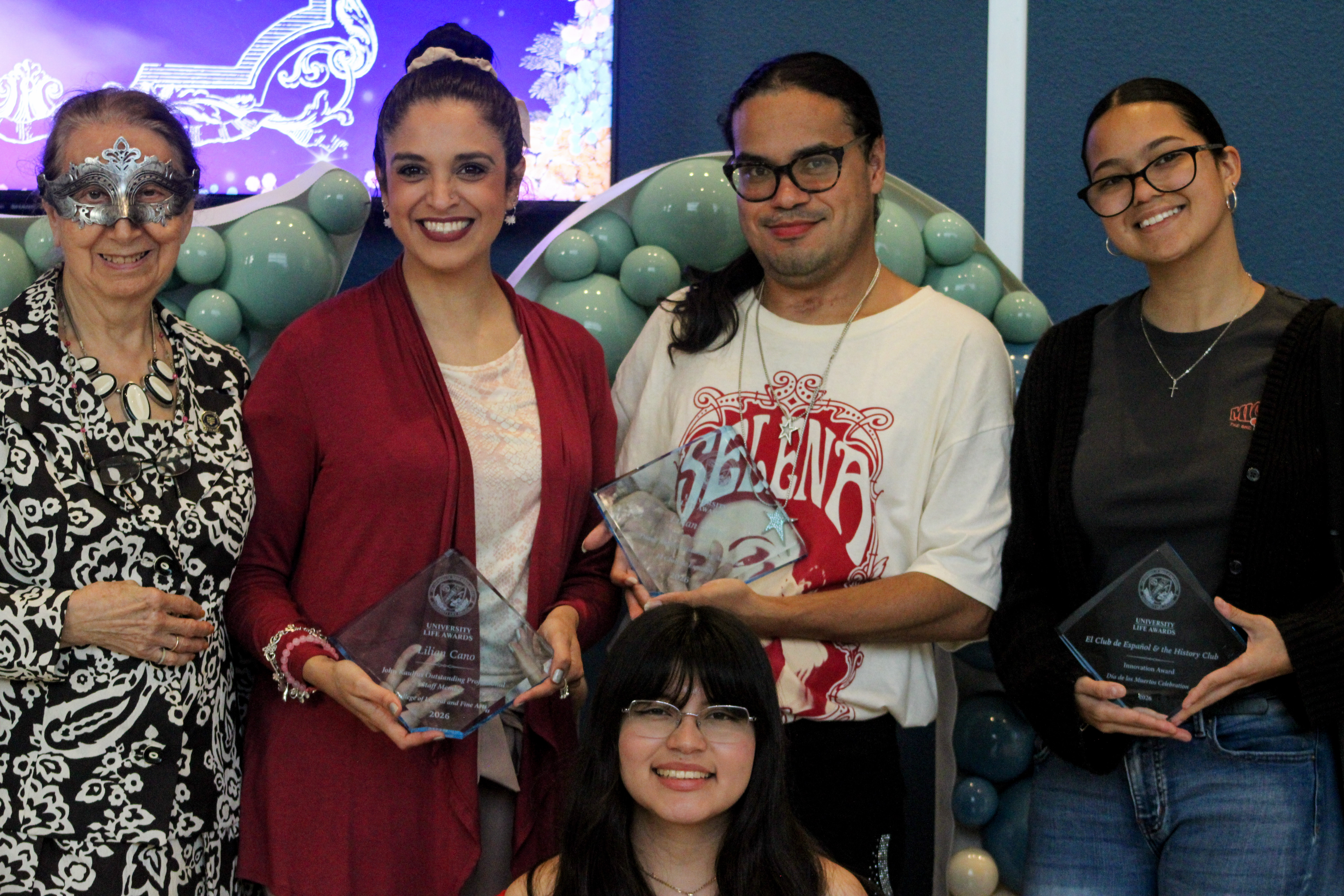 Two faculty members and three students holding plaques